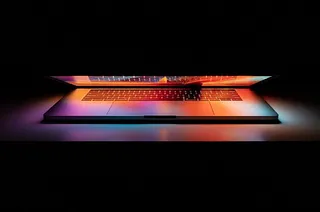 Ein offener Laptop im Dunkeln mit einem hellen, bunten Bildschirm.