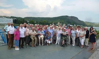 Eine große Gruppe älterer Menschen posiert für ein Foto im Freien.