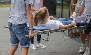 Zwei Menschen tragen eine Person auf einer Trage.