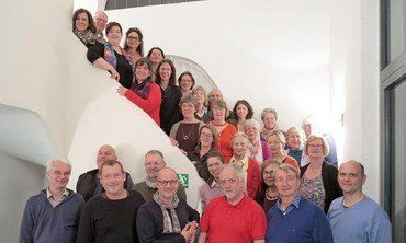 Eine große Gruppe von Menschen steht für ein Gruppenfoto auf und an einer Treppe.
