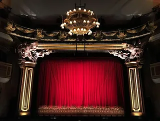 Roter Theatervorhang mit opulentem Rahmen und Kronleuchter.