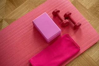 Yogamatte mit pinkem Block und Hanteln.