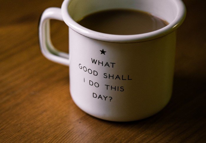 Weiße Tasse mit Text: „WHAT GOOD SHALL I DO THIS DAY?“.
