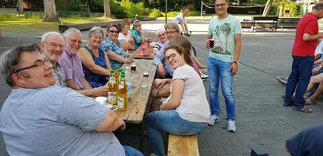 Eine Gruppe von Menschen sitzt an einem Holztisch im Freien.