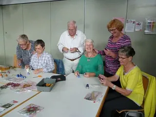 Eine Gruppe älterer Menschen bastelt an einem Tisch.