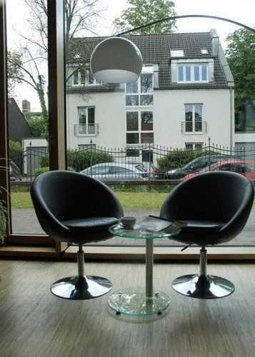Zwei Stühle an einem Tisch in einem Raum mit großen Fenstern.